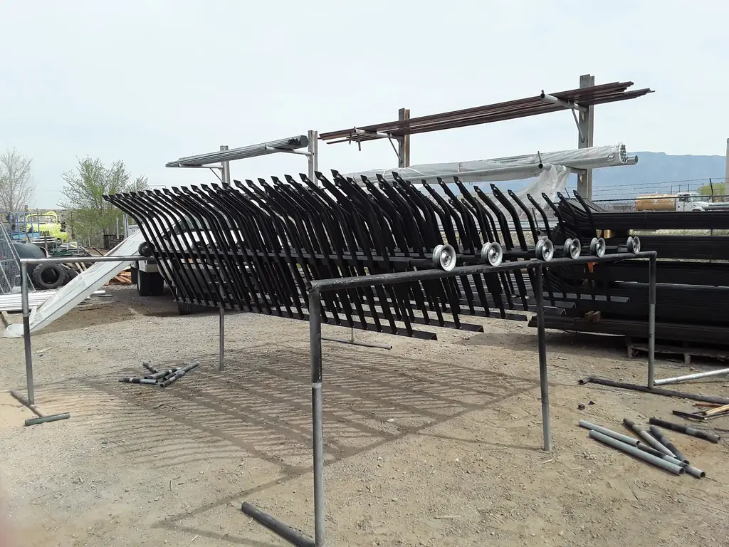 Rows of powder coated wrought iron fence panels and raw steel tube stock on racks in the Albuquerque Fence Company yard