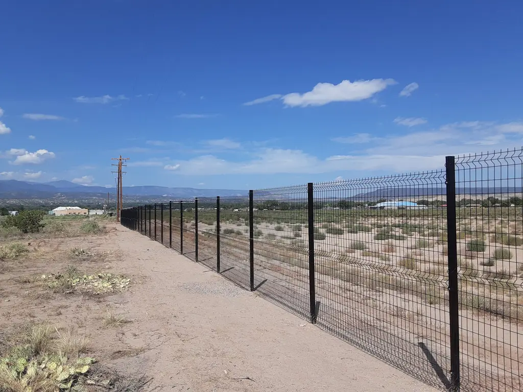Black welded wire perimeter fence running toward the mountains outside Albuquerque
