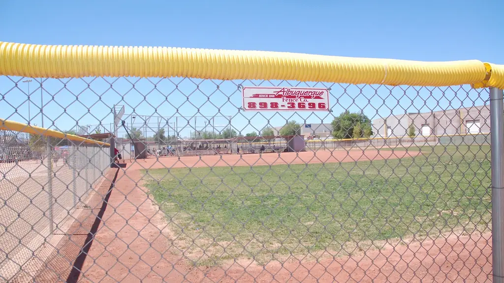 Chain link ballfield fence carrying the painted Albuquerque Fence Co. banner, since 1968
